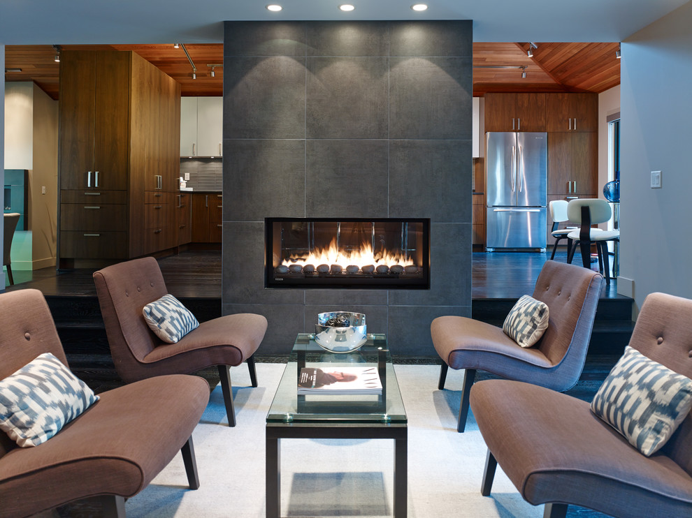 This is an example of a contemporary living room in Vancouver with dark hardwood flooring, a two-sided fireplace and a tiled fireplace surround.