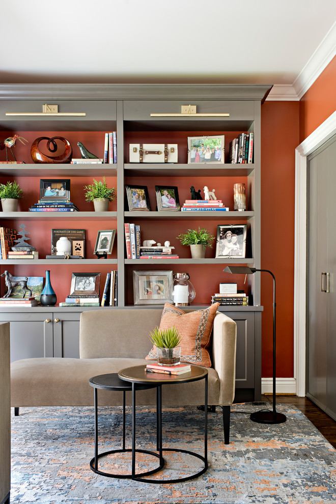 Inredning av ett klassiskt litet separat vardagsrum, med ett bibliotek, orange väggar, mörkt trägolv och brunt golv
