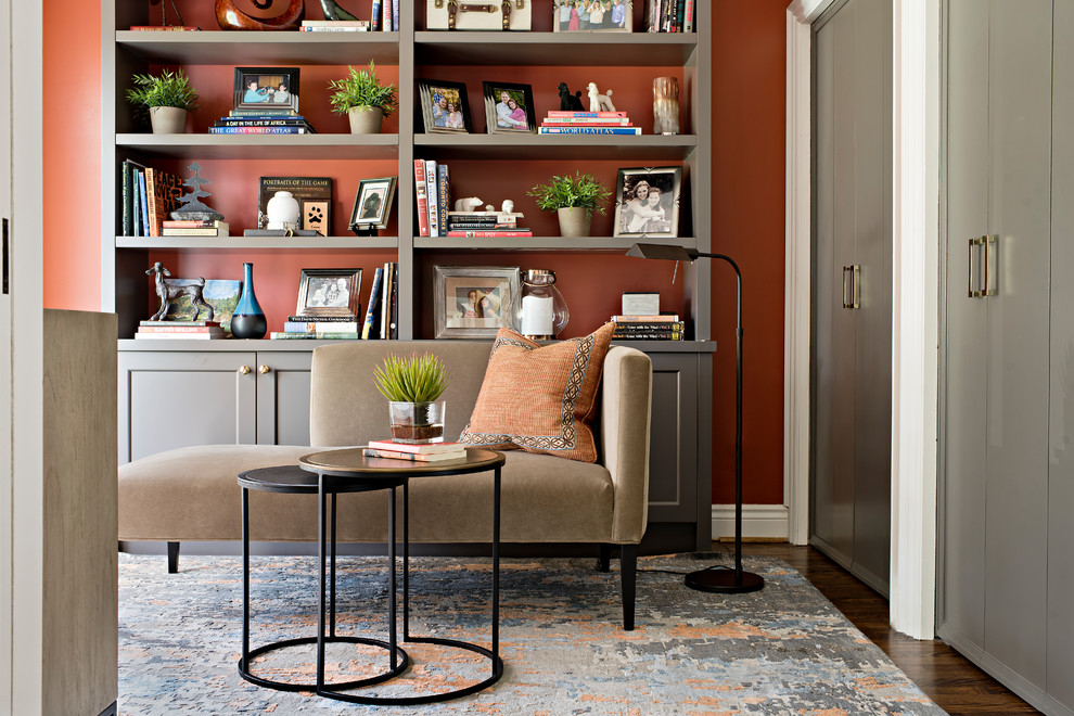 На фото: маленькая изолированная гостиная комната в стиле неоклассика (современная классика) с с книжными шкафами и полками, оранжевыми стенами, темным паркетным полом и коричневым полом без камина, телевизора для на участке и в саду