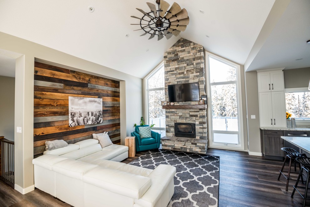 Mittelgroßes, Offenes Uriges Wohnzimmer mit grauer Wandfarbe, Vinylboden, Kaminofen, Kaminumrandung aus Stein und TV-Wand in Calgary