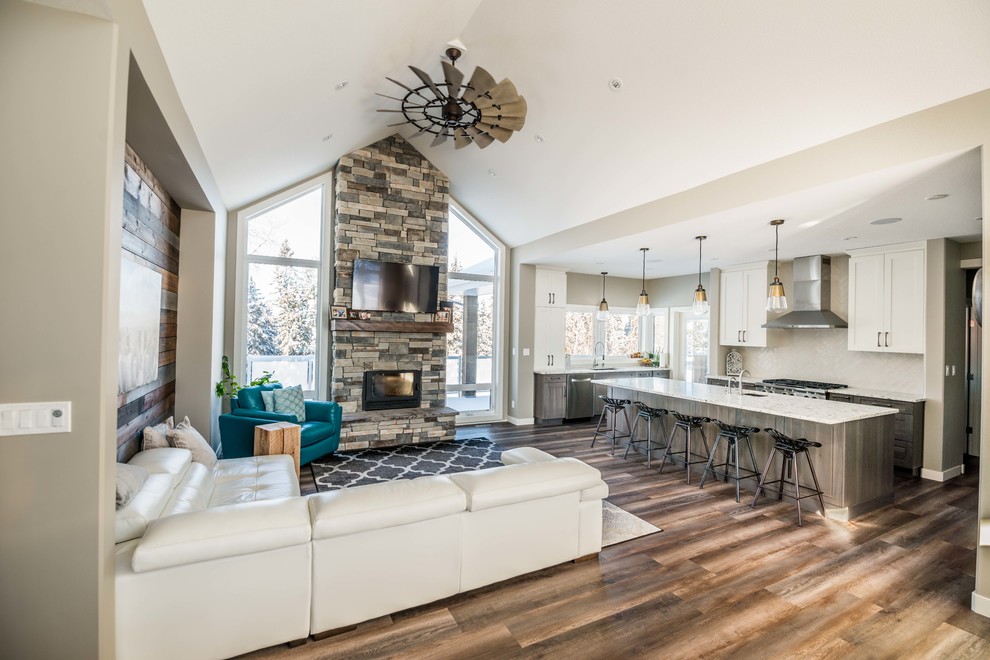Inspiration for a mid-sized rustic open concept vinyl floor living room remodel in Calgary with gray walls, a wood stove, a stone fireplace and a wall-mounted tv