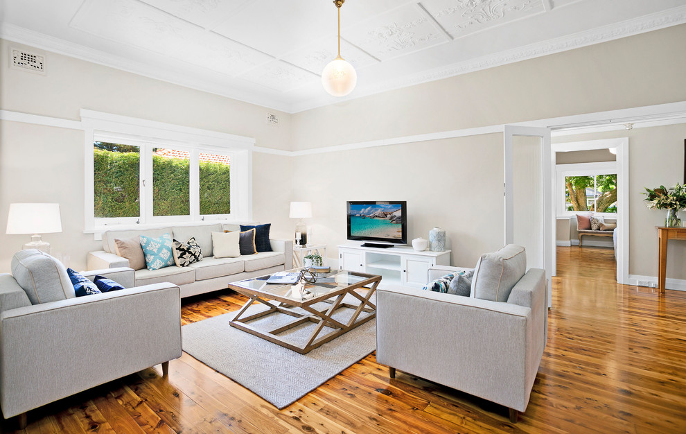 Ejemplo de salón abierto tradicional renovado de tamaño medio con paredes beige, suelo de madera en tonos medios y televisor independiente
