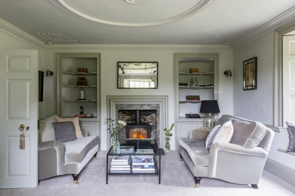 This is an example of a medium sized classic enclosed living room in Devon with green walls, carpet, a wood burning stove, a stone fireplace surround and grey floors.