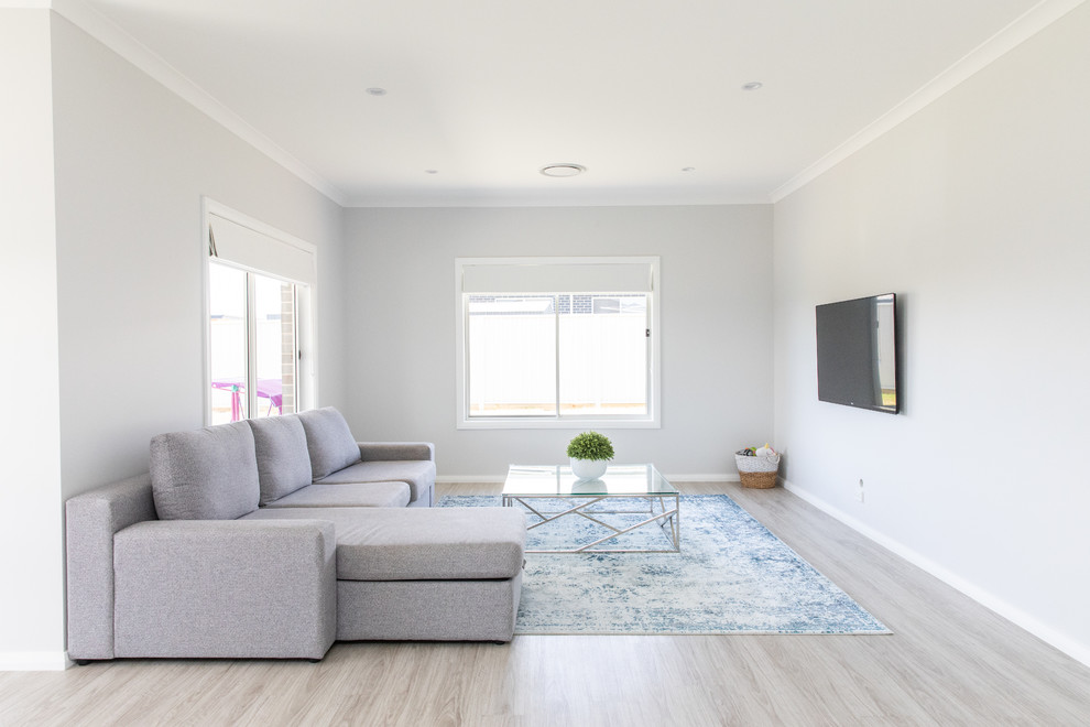Modelo de salón abierto minimalista grande con paredes grises, suelo vinílico, televisor colgado en la pared y suelo gris