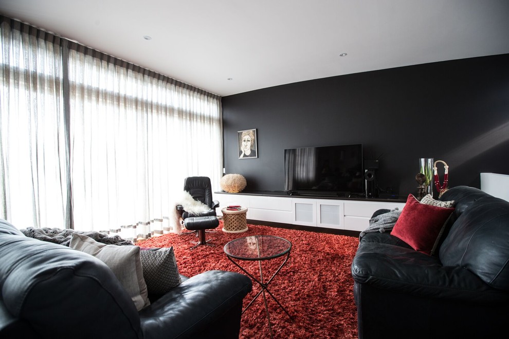 Urban loft-style medium tone wood floor living room photo in Melbourne with black walls