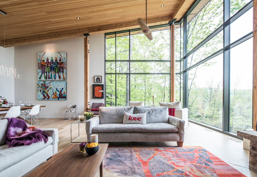 Ejemplo de salón abierto minimalista extra grande con paredes grises, suelo de madera clara, todas las chimeneas, marco de chimenea de piedra y televisor colgado en la pared