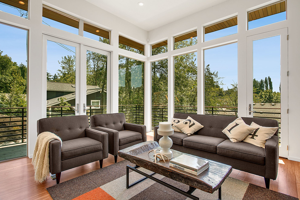 Example of a transitional medium tone wood floor living room design in Seattle with white walls