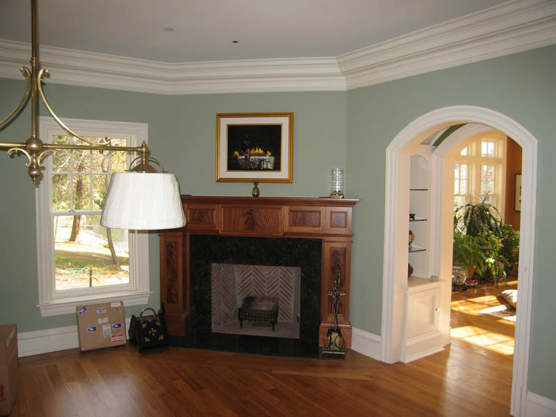 Mittelgroßes Klassisches Wohnzimmer mit grüner Wandfarbe, braunem Holzboden, Eckkamin und Kaminumrandung aus Stein in New York