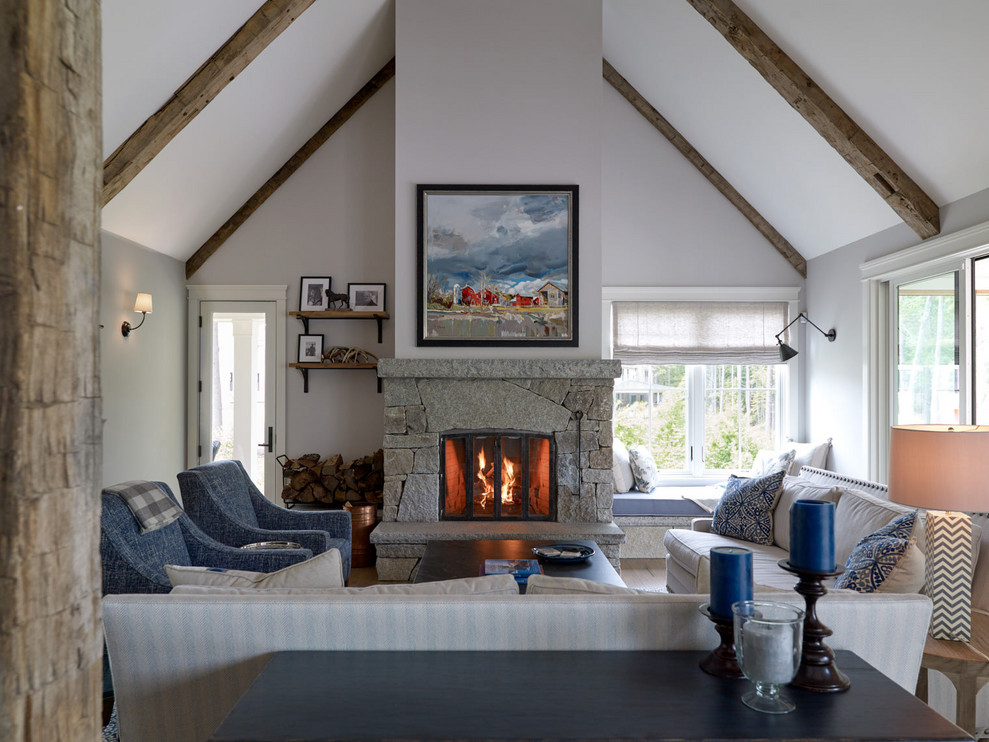 This is an example of a large traditional open plan living room in Portland Maine with white walls, a standard fireplace, a stone fireplace surround and a concealed tv.