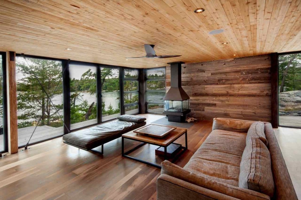 Modernes Wohnzimmer mit braunem Holzboden, Tunnelkamin und Kaminumrandung aus Holz in Toronto