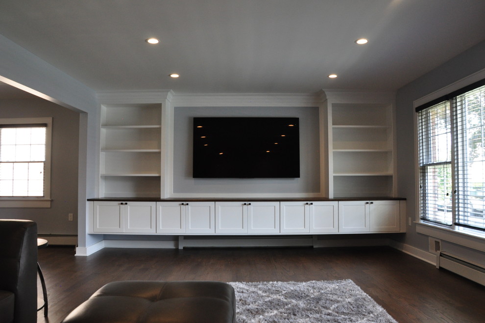 Modelo de salón abierto clásico renovado grande con paredes grises, suelo de madera en tonos medios, suelo marrón y pared multimedia