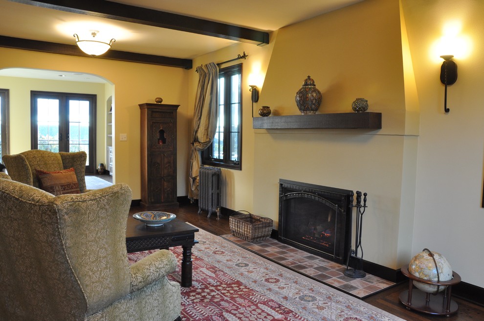 Стильный дизайн: гостиная комната среднего размера в стиле неоклассика (современная классика) с желтыми стенами, темным паркетным полом, стандартным камином и фасадом камина из штукатурки - последний тренд
