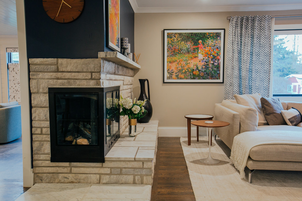 Geräumiges, Offenes Klassisches Wohnzimmer mit grauer Wandfarbe, braunem Holzboden, Eckkamin, Kaminumrandung aus Stein, TV-Wand und braunem Boden in Denver
