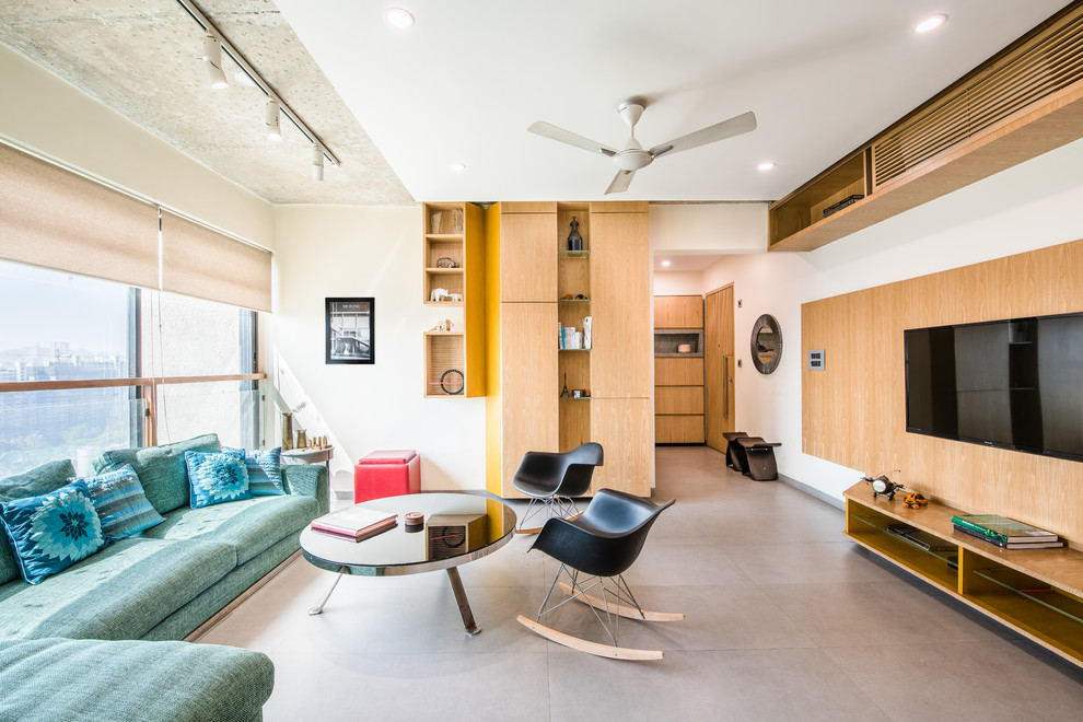 Modernes Wohnzimmer ohne Kamin mit weißer Wandfarbe, Betonboden und Multimediawand in Mumbai