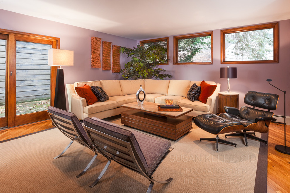 Cette photo montre un grand salon rétro ouvert avec un mur violet et un sol en bois brun.