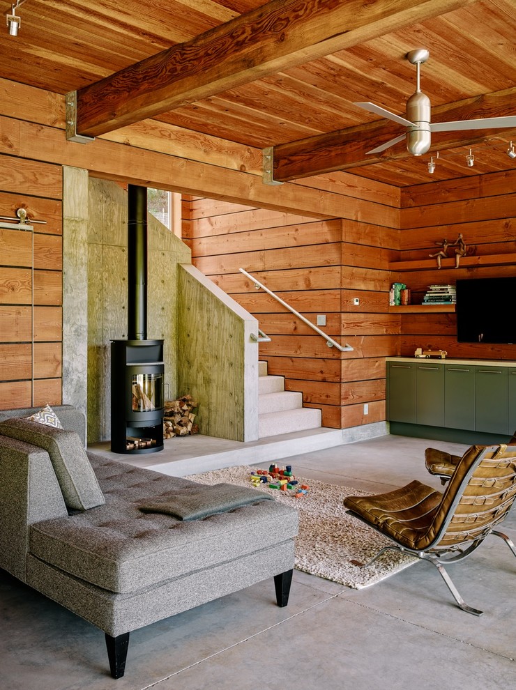 Источник вдохновения для домашнего уюта: гостиная комната в современном стиле с бетонным полом, телевизором на стене и печью-буржуйкой