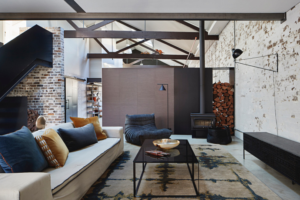 На фото: гостиная комната в стиле лофт с бетонным полом, печью-буржуйкой, сводчатым потолком и кирпичными стенами с
