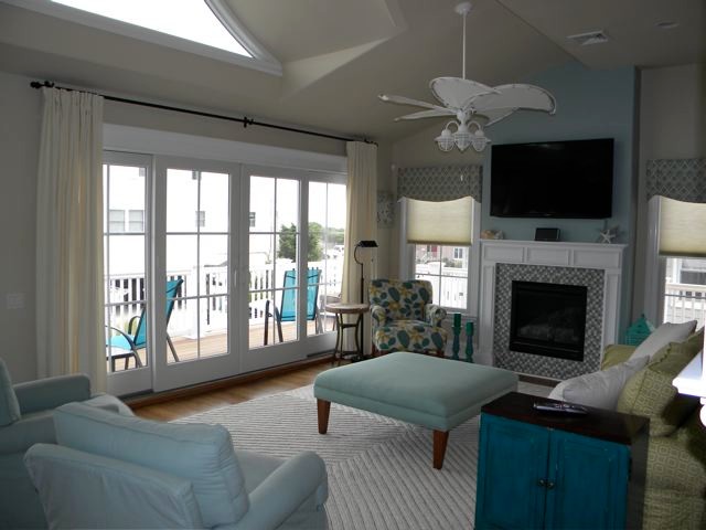Пример оригинального дизайна: огромная открытая гостиная комната в морском стиле с бежевыми стенами, паркетным полом среднего тона, стандартным камином, фасадом камина из дерева и телевизором на стене