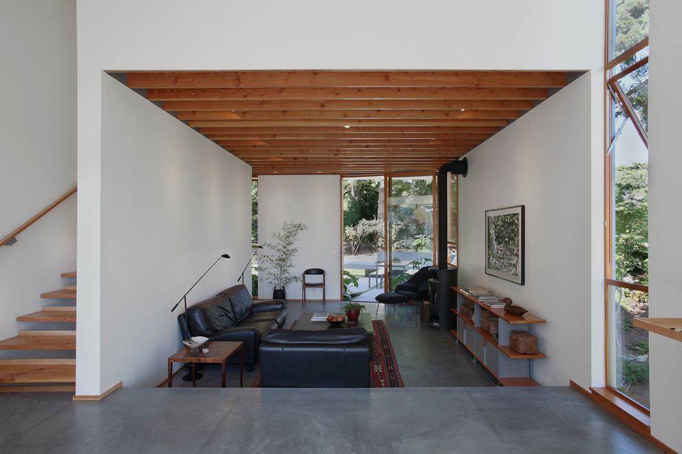 This is an example of a contemporary living room in Seattle with white walls and a wood burning stove.