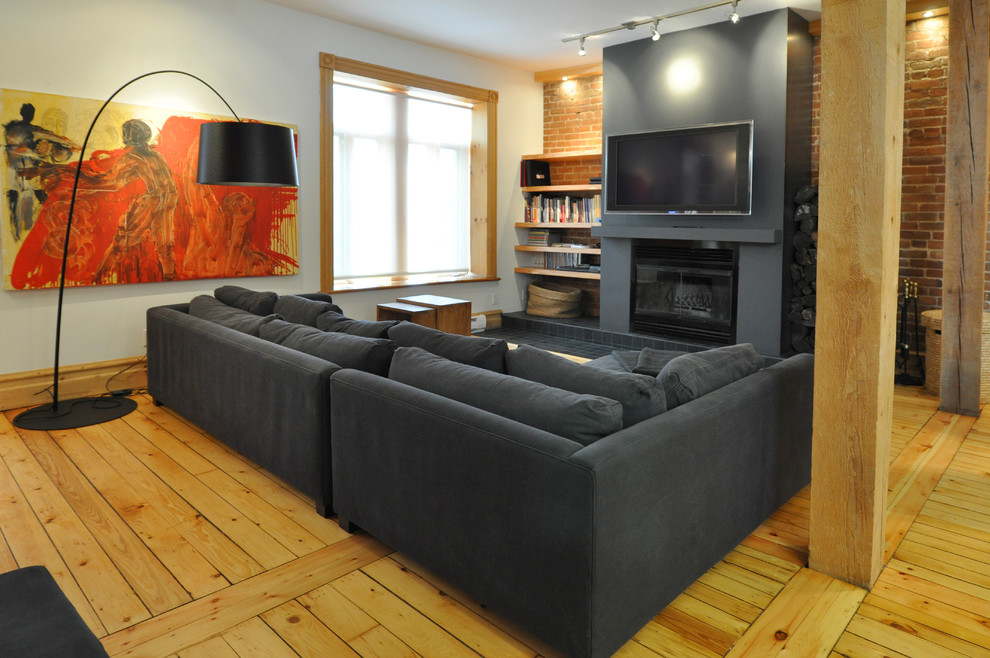 Inredning av ett modernt vardagsrum, med mellanmörkt trägolv, en väggmonterad TV och gult golv