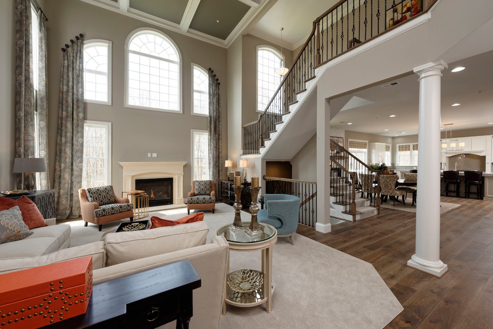 Aménagement d'un salon classique ouvert avec un mur beige, un sol en bois brun, une cheminée standard, un sol marron et un escalier.