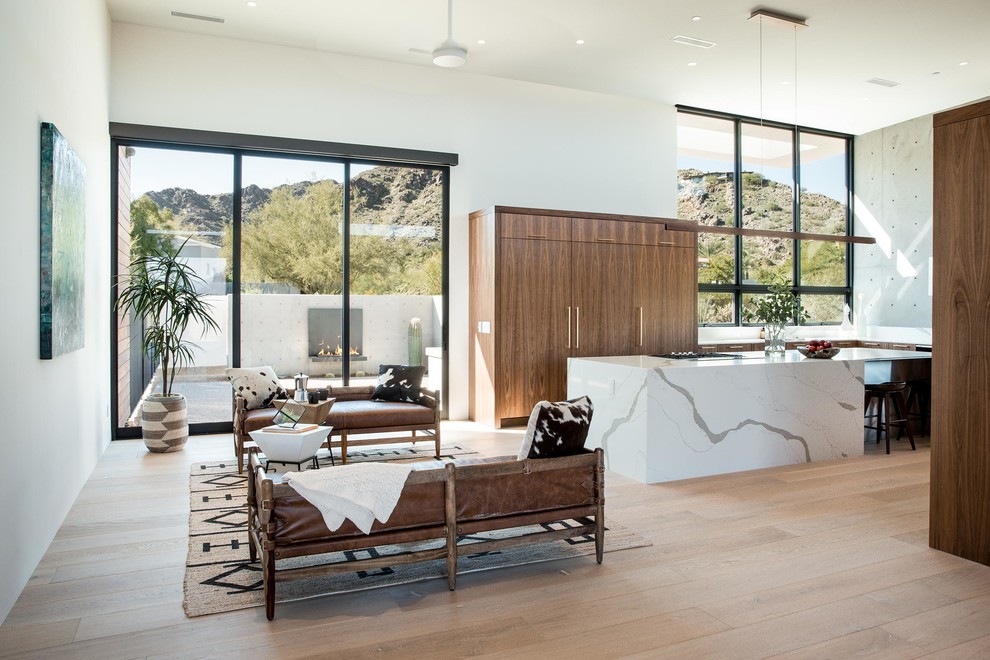 Modelo de salón para visitas abierto de estilo americano sin chimenea y televisor con paredes blancas, suelo de madera clara y suelo beige