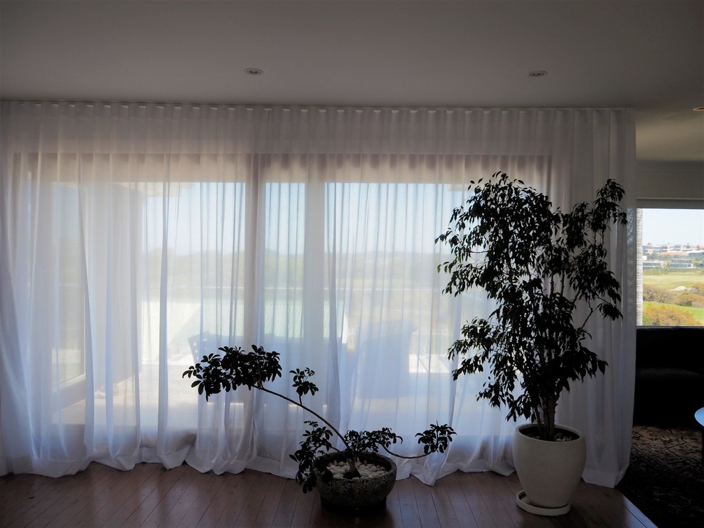 Bild på ett minimalistiskt vardagsrum, med vita väggar och ljust trägolv