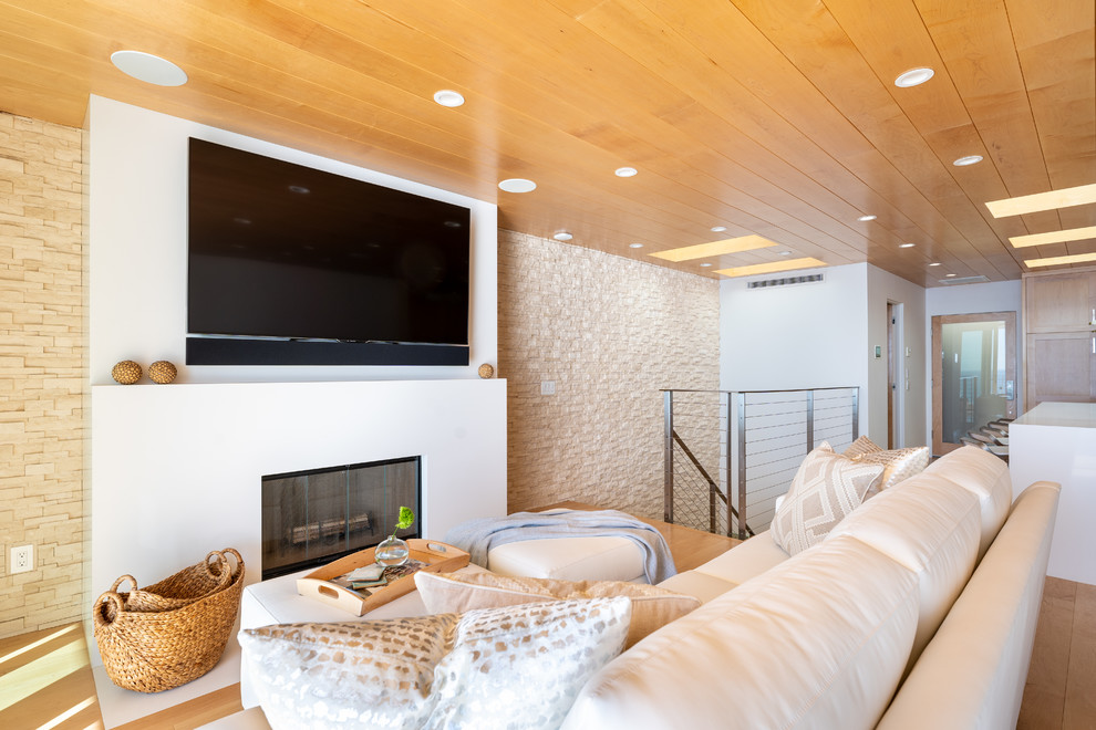 Свежая идея для дизайна: огромная открытая гостиная комната в современном стиле с белыми стенами, светлым паркетным полом, стандартным камином, фасадом камина из камня, телевизором на стене и желтым полом - отличное фото интерьера