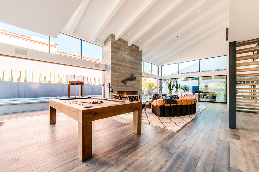 This is an example of an expansive contemporary open plan living room in Los Angeles with a ribbon fireplace, a concrete fireplace surround, white walls, grey floors and medium hardwood flooring.