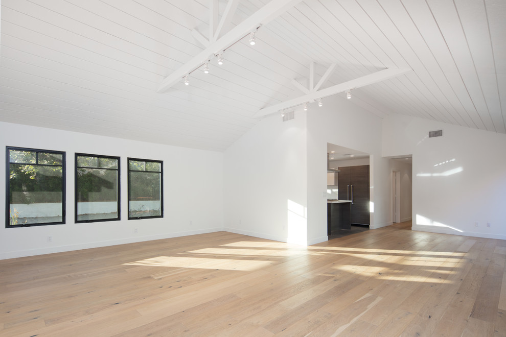 Ejemplo de salón abierto campestre de tamaño medio con paredes blancas, suelo de madera clara y televisor colgado en la pared