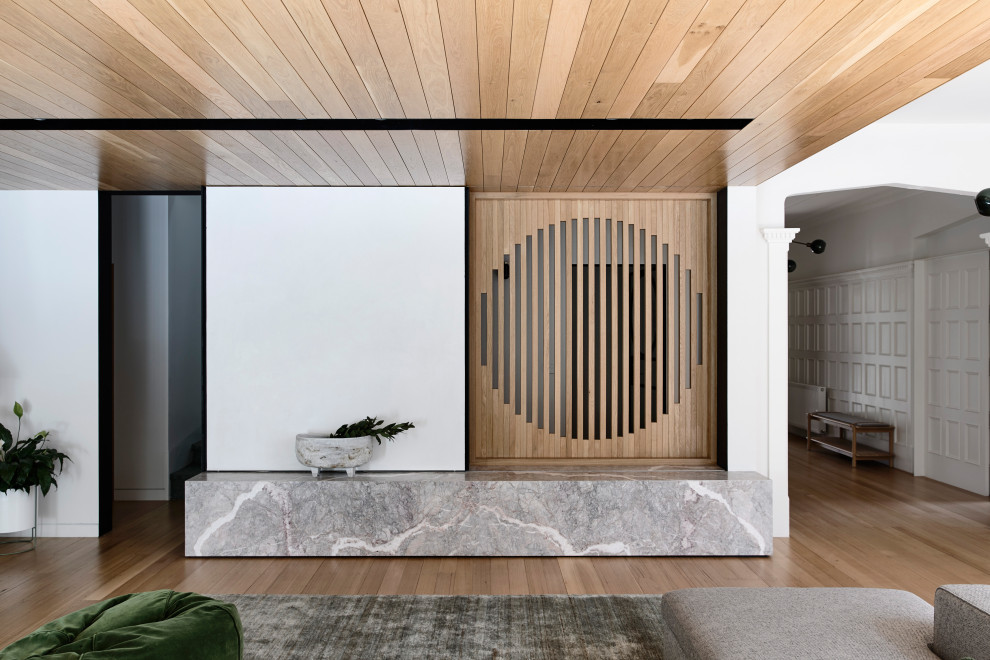 Imagen de salón abierto contemporáneo de tamaño medio con paredes blancas, suelo de madera en tonos medios, televisor retractable y suelo marrón