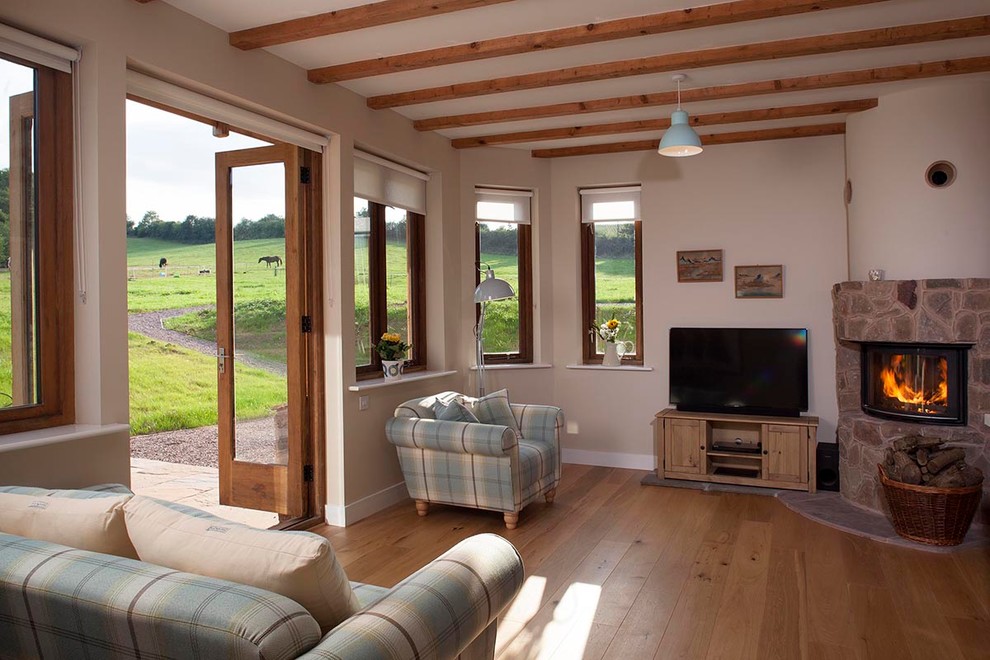 Kleine Landhausstil Bibliothek mit beiger Wandfarbe, braunem Holzboden, Eckkamin und freistehendem TV in Cornwall