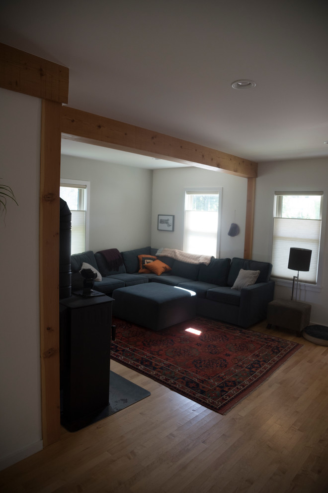 Источник вдохновения для домашнего уюта: открытая гостиная комната в скандинавском стиле с желтыми стенами, светлым паркетным полом и печью-буржуйкой