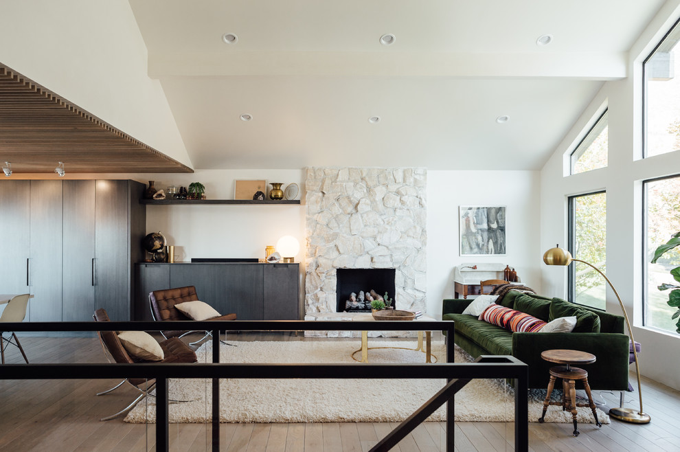 Immagine di un soggiorno minimalista di medie dimensioni e aperto con pareti bianche, parquet chiaro, camino classico, cornice del camino in pietra e TV nascosta