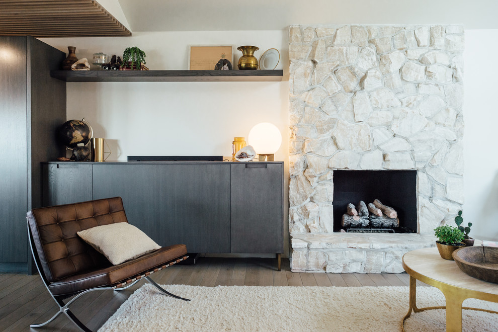 Inspiration pour un salon vintage de taille moyenne avec un mur blanc, parquet clair, une cheminée standard, un manteau de cheminée en pierre et un téléviseur dissimulé.