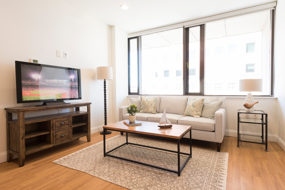 Immagine di un piccolo soggiorno chic aperto con pareti beige, pavimento in legno massello medio e TV autoportante