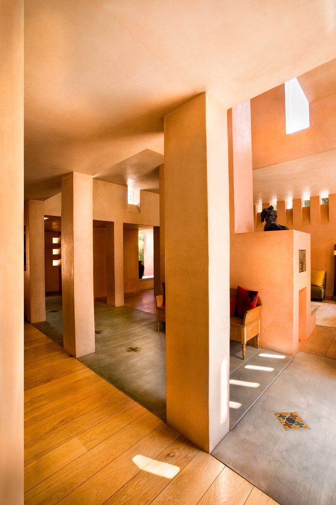 Идея дизайна: огромная узкая прихожая: освещение в средиземноморском стиле с оранжевыми стенами, бетонным полом, одностворчатой входной дверью, входной дверью из темного дерева, серым полом и сводчатым потолком