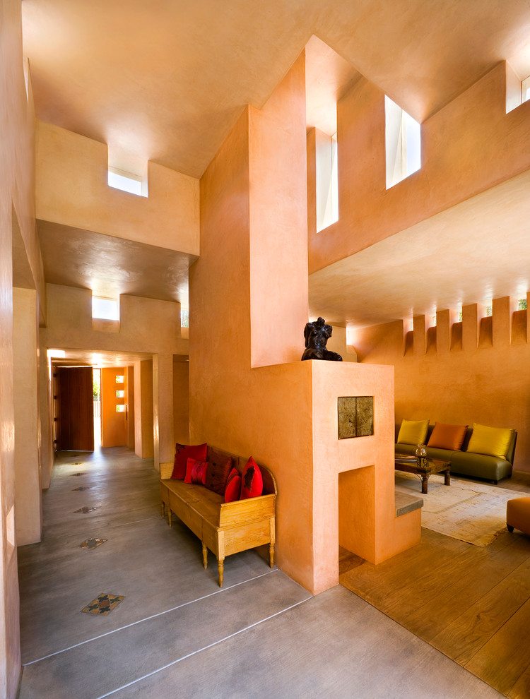 На фото: огромное фойе: освещение в средиземноморском стиле с оранжевыми стенами, светлым паркетным полом, одностворчатой входной дверью, входной дверью из темного дерева, бежевым полом и сводчатым потолком