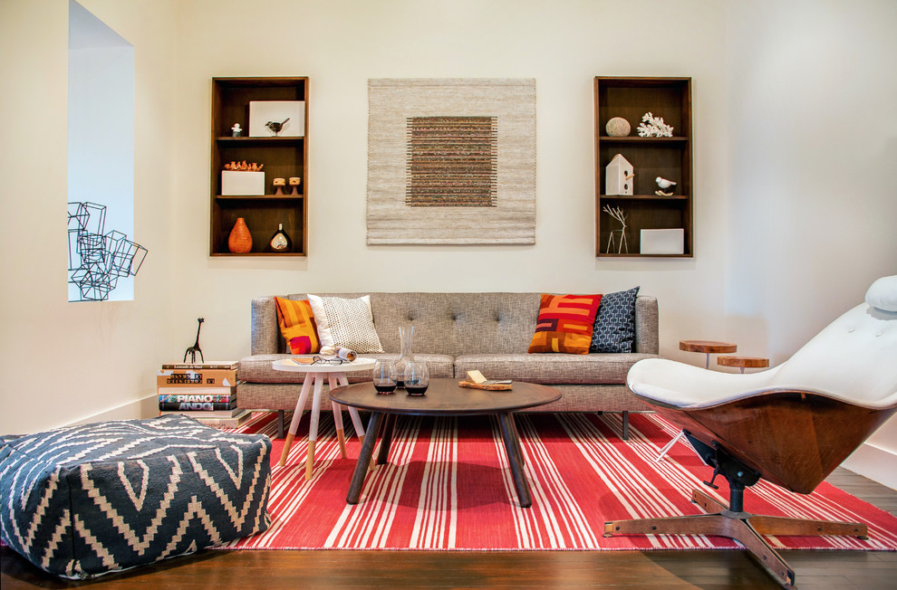 Cette image montre un salon design avec un mur blanc, un sol marron et parquet foncé.