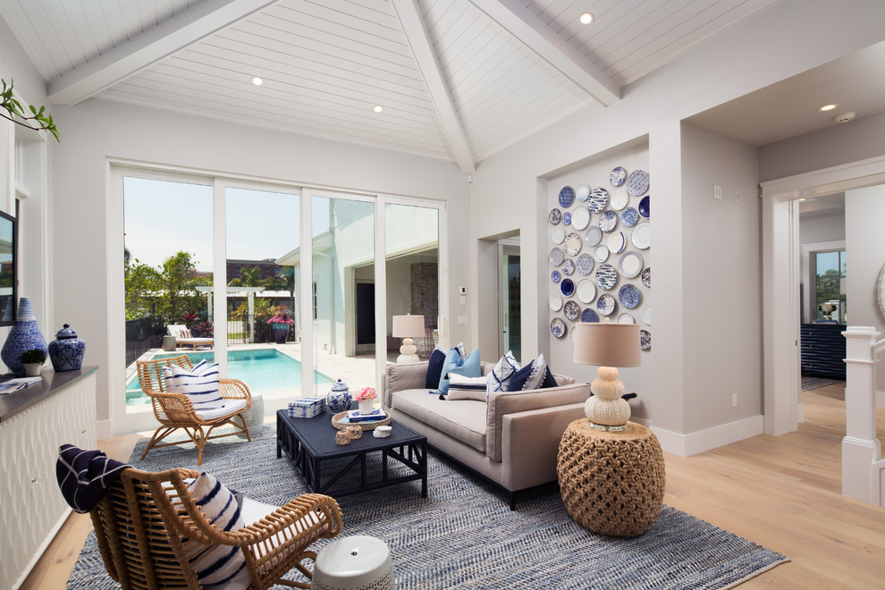 Mittelgroßes, Offenes Maritimes Wohnzimmer mit weißer Wandfarbe, braunem Holzboden und TV-Wand in Miami