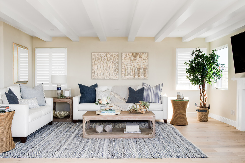 Esempio di un soggiorno stile marinaro di medie dimensioni con parquet chiaro, camino classico, TV a parete, pareti beige e pavimento beige