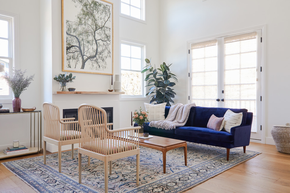 Пример оригинального дизайна: парадная, открытая гостиная комната в морском стиле с белыми стенами, светлым паркетным полом, горизонтальным камином, бежевым полом, синим диваном и ковром на полу без телевизора