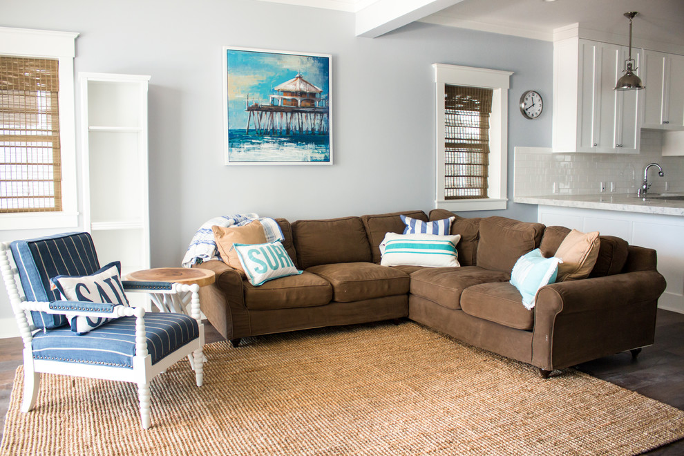 На фото: открытая гостиная комната среднего размера в морском стиле с серыми стенами, темным паркетным полом и коричневым диваном с