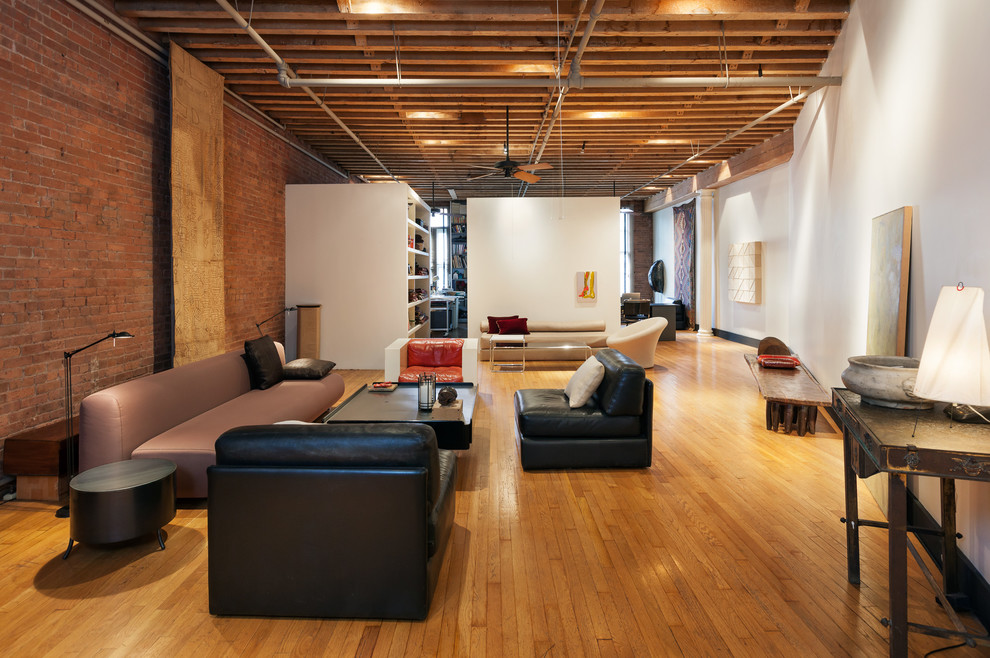Cette image montre un salon urbain ouvert avec un mur blanc et un sol en bois brun.