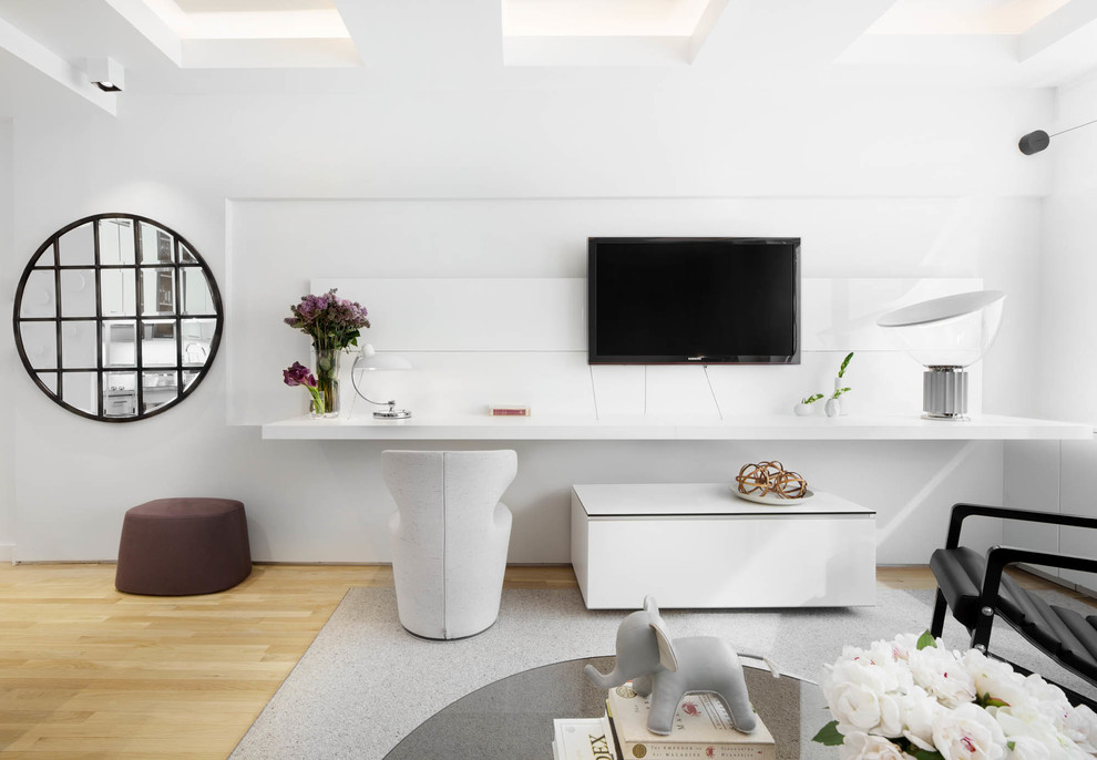 This is an example of a small modern open plan living room in New York with white walls, light hardwood flooring and a wall mounted tv.