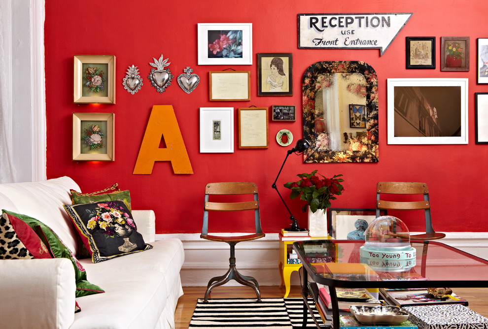 Idée de décoration pour un salon bohème avec un mur rouge et un sol en bois brun.