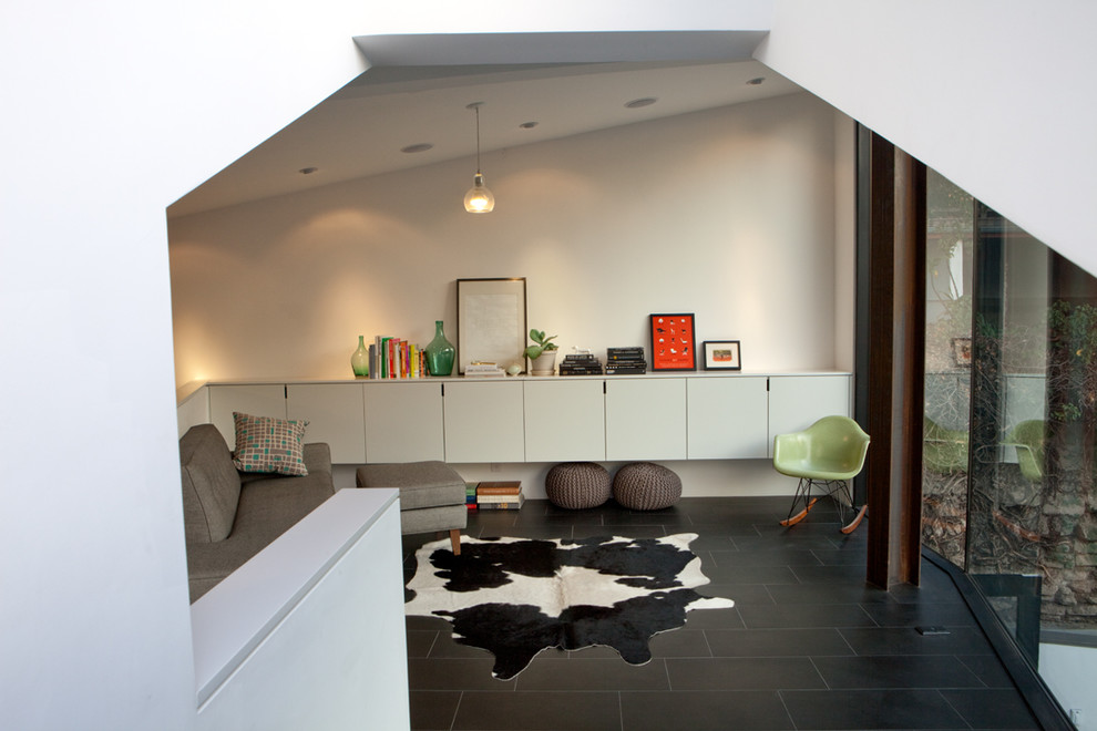 Foto di un piccolo soggiorno minimal stile loft con libreria, pareti bianche, pavimento in gres porcellanato e pavimento nero