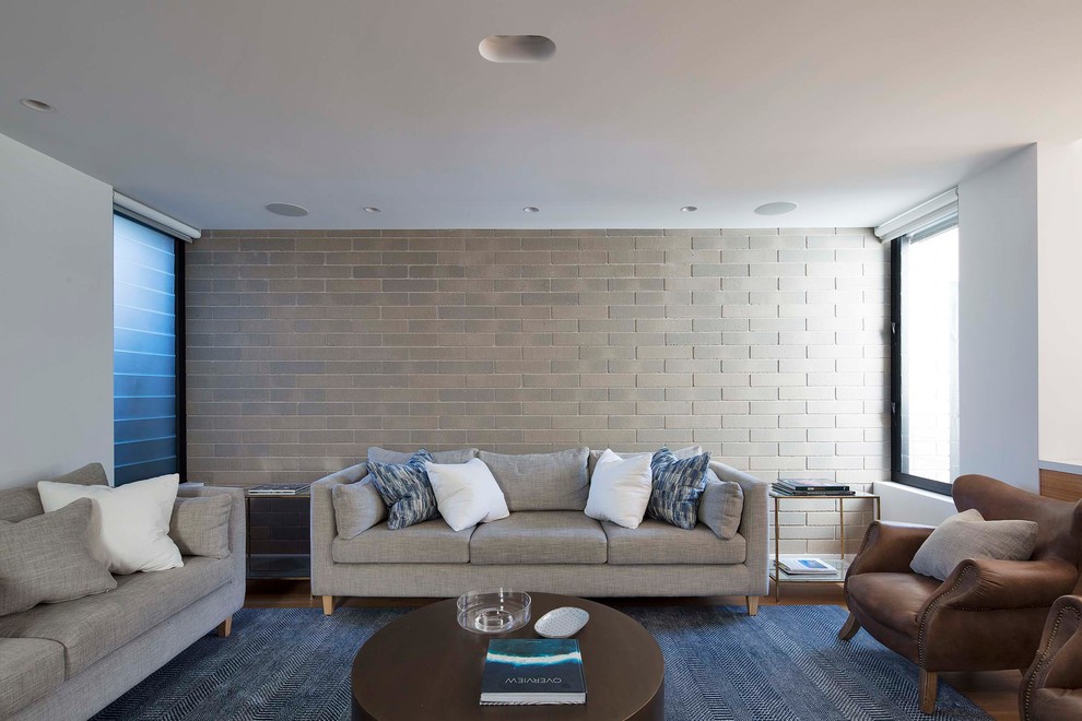 Diseño de salón abierto moderno sin chimenea con paredes blancas, suelo de madera en tonos medios y televisor colgado en la pared