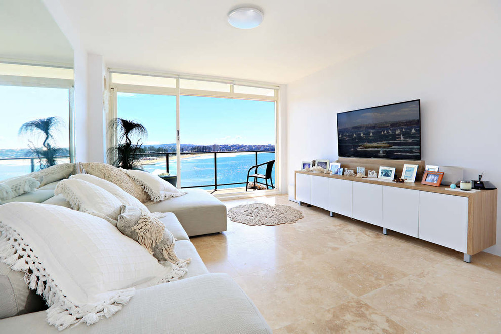 Photo of a coastal living room in Sydney with yellow walls, travertine flooring and a freestanding tv.