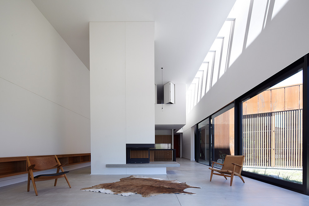 Großes Modernes Wohnzimmer mit weißer Wandfarbe, Betonboden, Tunnelkamin und verputzter Kaminumrandung in Melbourne